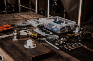 Assorted plumbing tools and parts on wooden workbench.